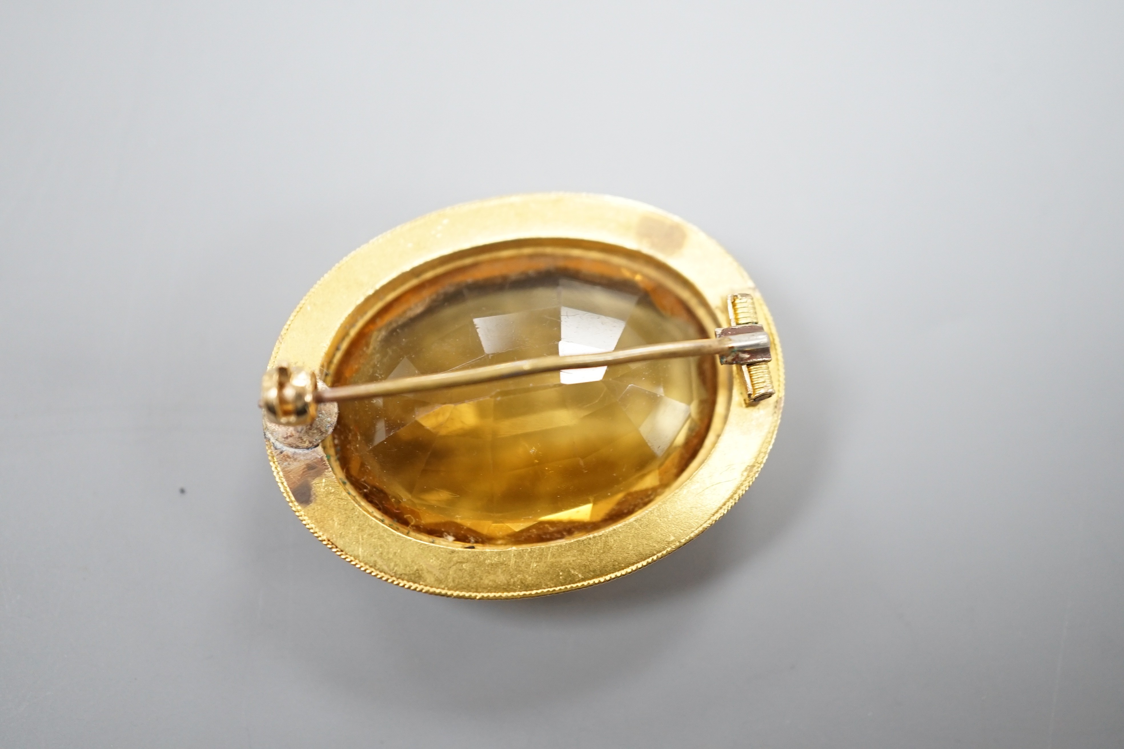 A Victorian yellow metal and citrine set oval brooch, with cannetille work border, 35mm, gross weight 11.3 grams.